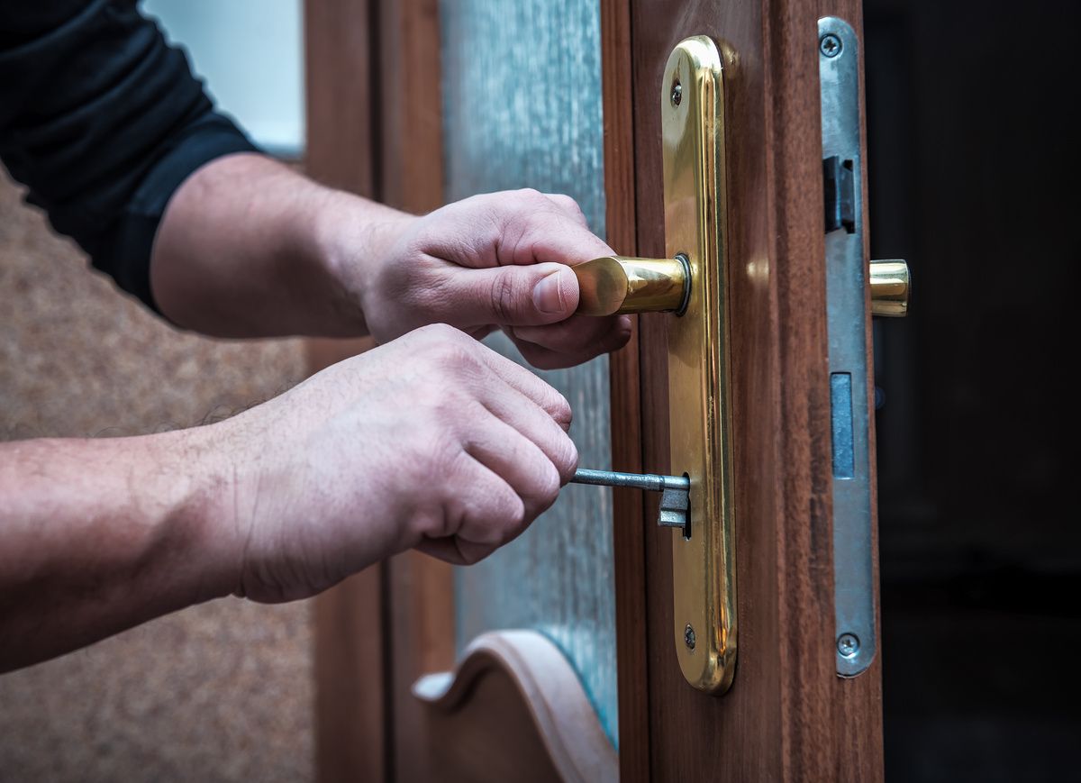 A hand turning a key in a front door lock